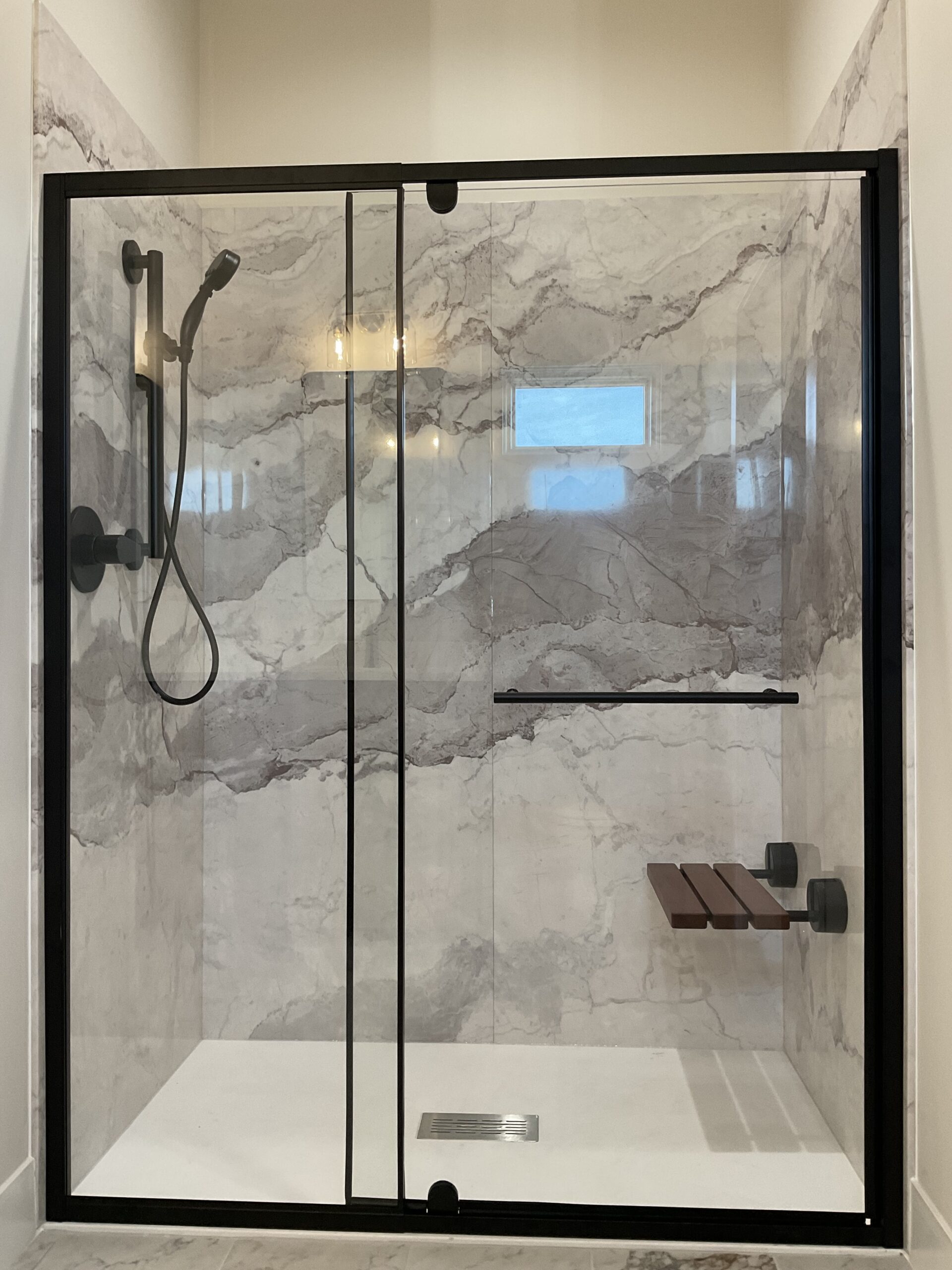 Enclosed Roll-in Shower with fold-down seat, grab bar with adjustable height shower head.